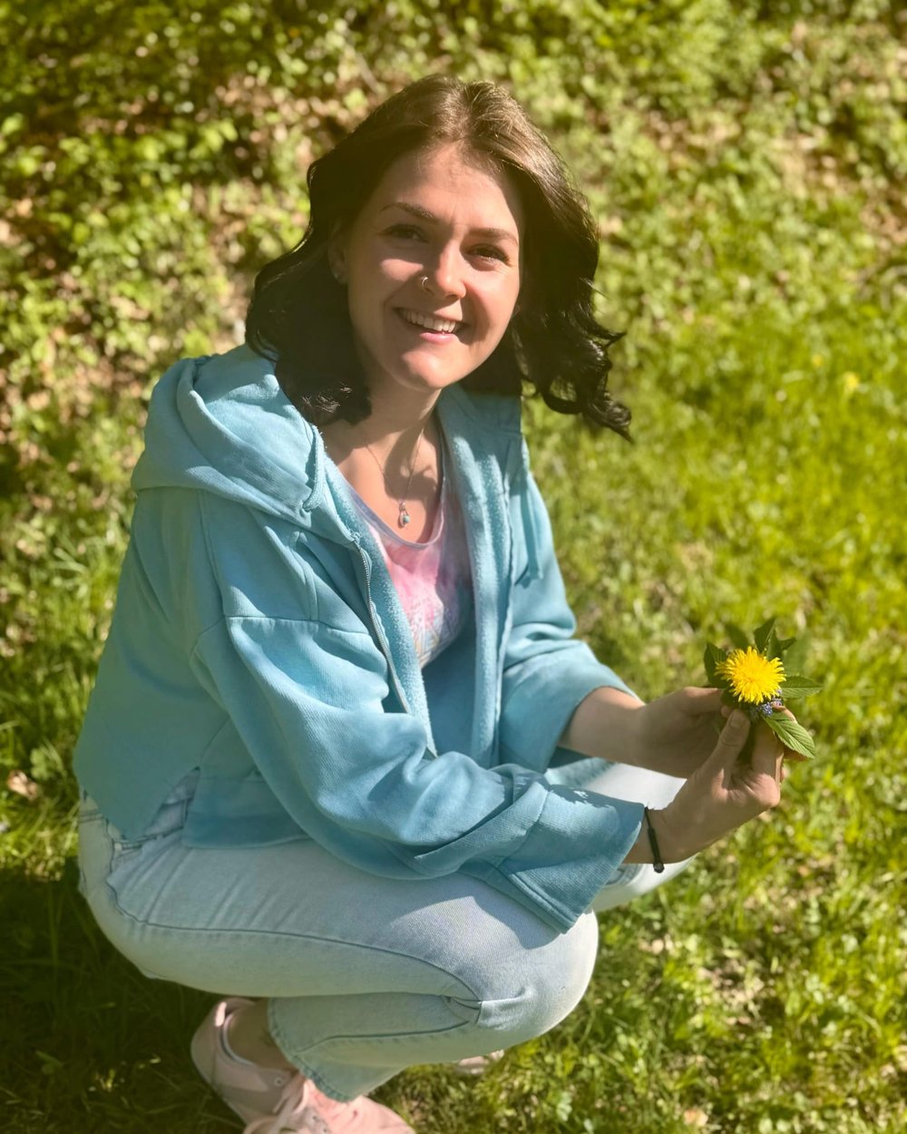 Victoria Ellmauthaler in einer grünen Wiese mit einer gelben Blume in der Hand
